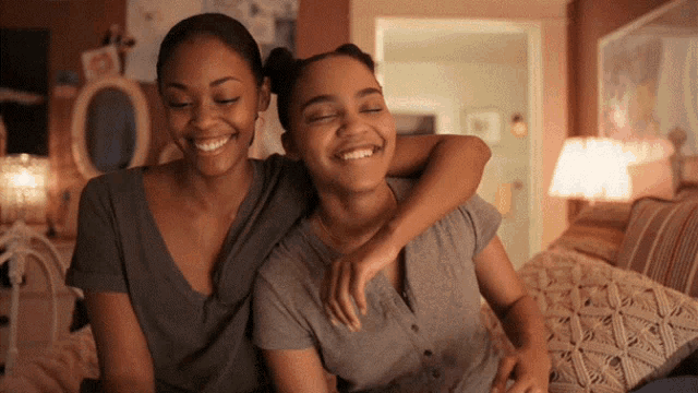 two girls are sitting on a couch and smiling for the camera