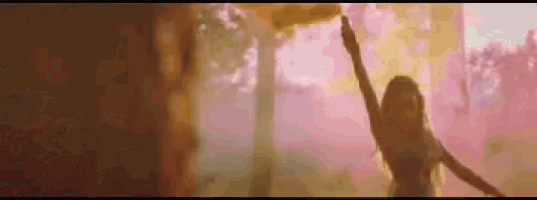 a woman is holding a pink smoke bomb in her hand and dancing in the woods .