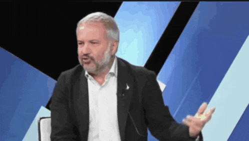 a man with a beard is sitting in front of a microphone