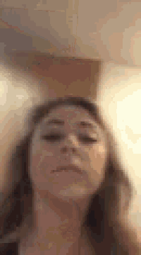 a woman is making a funny face while looking at the camera in a blurry photo .