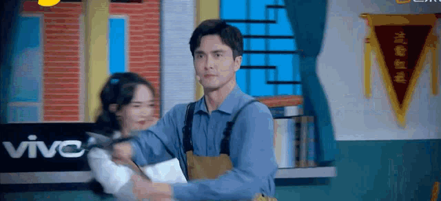 a man is holding a woman in his arms in front of a vivo sign .