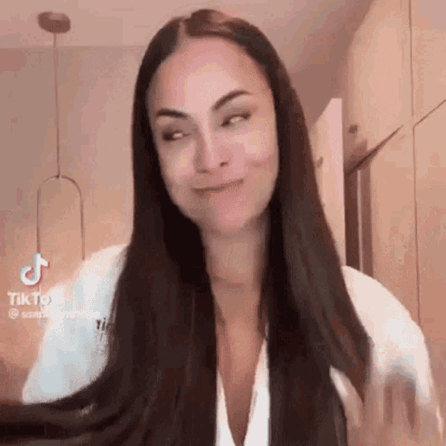 a woman with long dark hair is making a funny face while holding her hair .