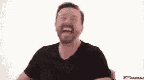 a man with a beard is sitting in a chair laughing .