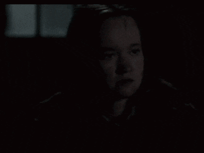 a close up of a woman 's face in the dark with a scar on her forehead