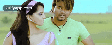 a man and a woman are standing next to each other in a field . the man is wearing a green shirt .
