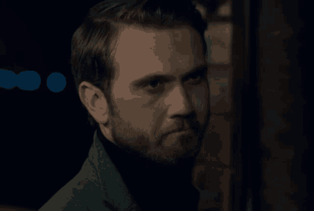 a man with a beard looks at the camera