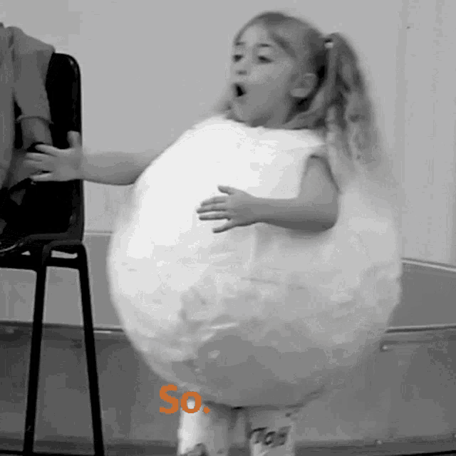 a little girl is standing in front of a chair wearing a costume that looks like a balloon with the word so on it