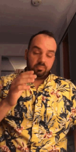 a man with a beard wearing a yellow shirt with flowers on it