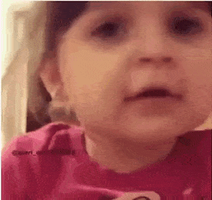 a close up of a baby 's face with a pink shirt on .