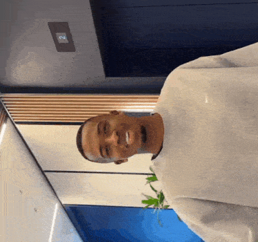 a man wearing a grey nike sweatshirt smiles in an elevator