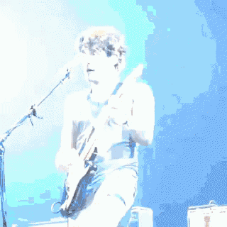 a man is playing a guitar in front of a microphone .