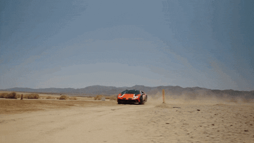 a red sports car is driving through a sandy desert