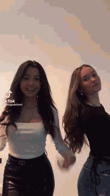 two young women are holding hands and dancing together .