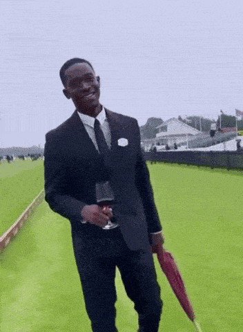 a man in a suit and tie holding a glass of wine and an umbrella
