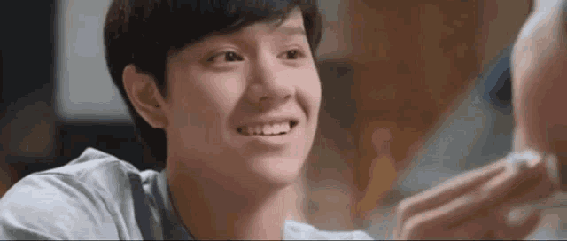 a young man is smiling and looking at another person 's face .