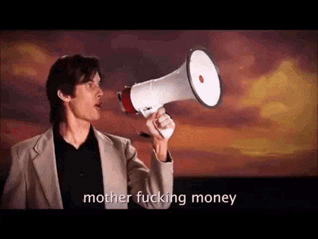 a man in a suit is holding a megaphone and screaming into it .