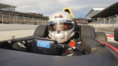 a man wearing a stilb helmet sits in a racing car