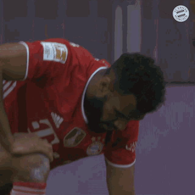 a man in a bayern munich shirt is laying on the ground