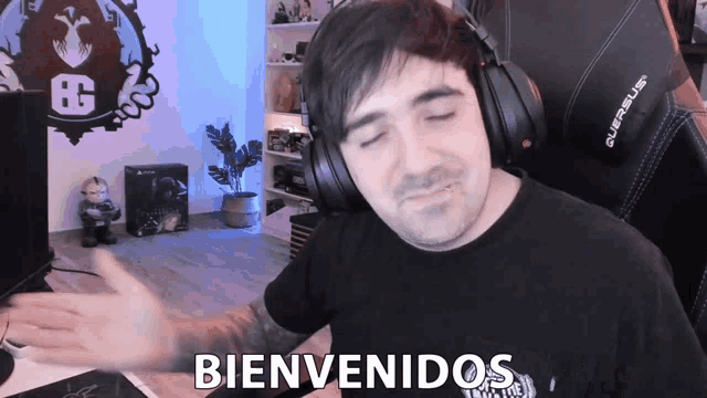 a man wearing headphones says bienvenidos in front of a gaming chair
