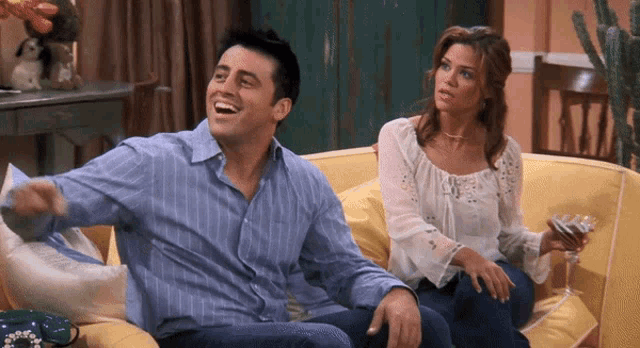 a man and a woman sit on a yellow couch