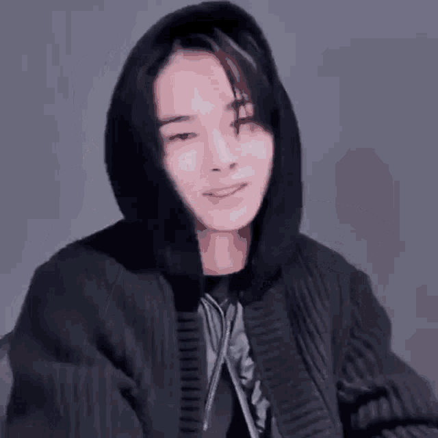 a young man wearing a black hoodie and a black jacket .