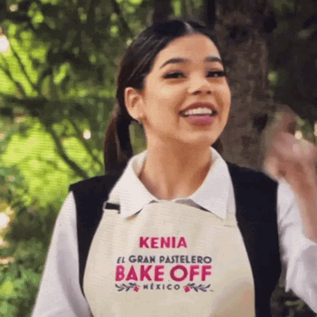 a woman wearing an apron that says kenia el gran pastelero bake off mexico on it