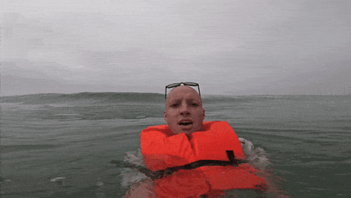 a man wearing an orange life jacket is floating in the water