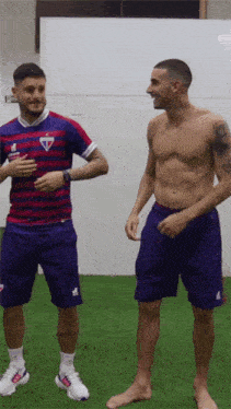 a shirtless man is standing next to another shirtless man in shorts