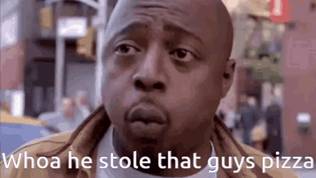 a man is standing on a city street with the words `` whoa he stole that guys pizza '' written on the bottom .