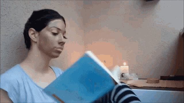 a woman is reading a book with a candle in the background .