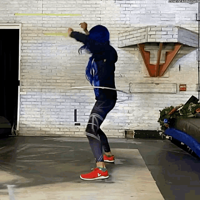 a woman with blue hair is holding a hula hoop in front of a brick wall ..