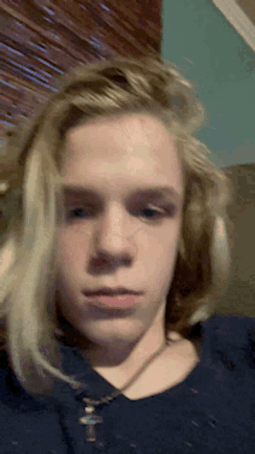 a young man with blonde hair is wearing a blue shirt