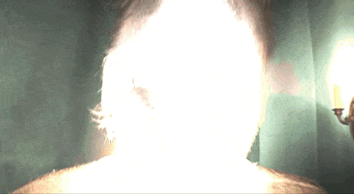 a person 's head is glowing brightly in front of a green wall