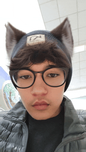 a young man wearing glasses and a beanie with the letter k on the label