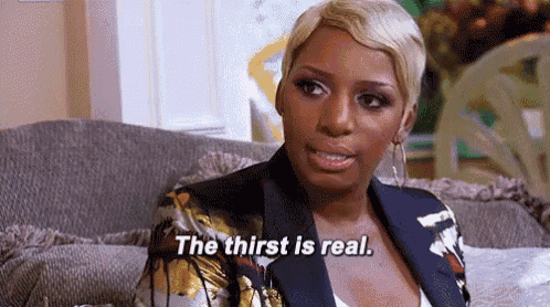 a woman is sitting on a couch and talking about the thirst is real .