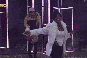 a woman in a white coat is dancing in front of a sign that says bbc