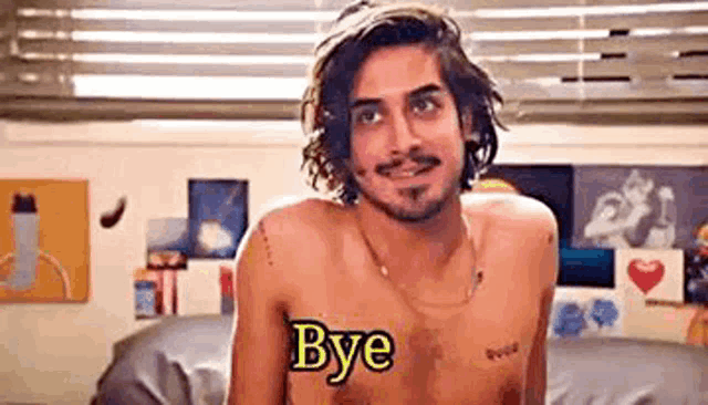 a shirtless man is sitting on a couch with the words `` bye '' written on his chest .