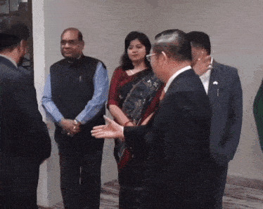 a man in a suit talks to a woman in a sari