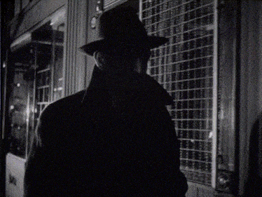 a black and white photo of a man wearing a hat and a coat