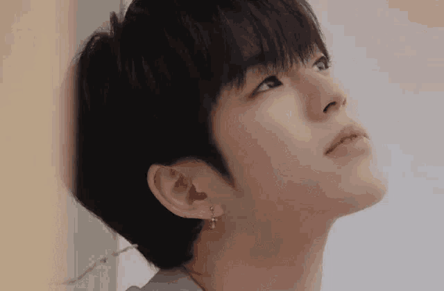 a close up of a young man 's face wearing earrings .