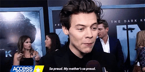 harry styles is talking into a microphone while standing in front of a crowd at a movie premiere .