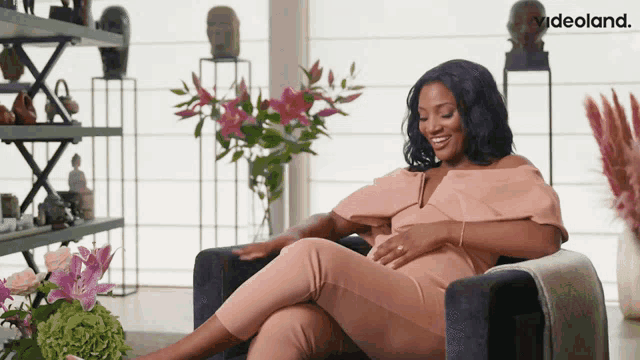 a pregnant woman is sitting in a chair with videoland written in the corner