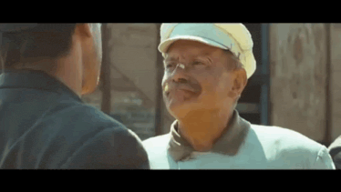 a man with a mustache is talking to another man in a movie .