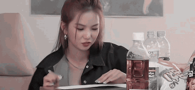 a woman is sitting at a table with a bottle of water and a bag of chips ..