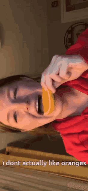 a girl in a red shirt is eating an orange and the caption says i dont actually like oranges