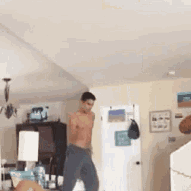 a shirtless man is dancing in a living room without a shirt .