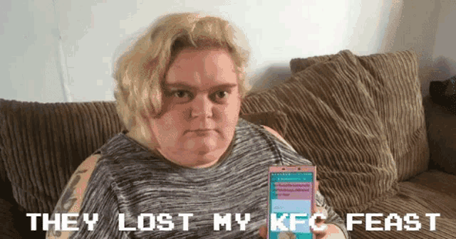 a woman sits on a couch holding a box of kfc feast