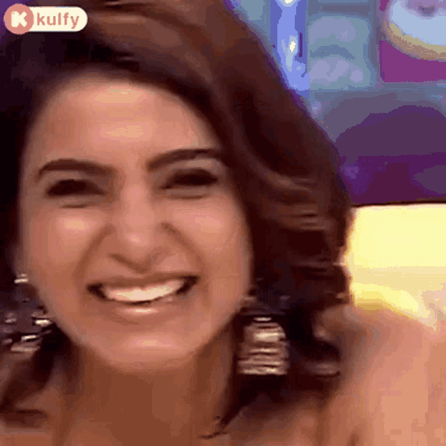 a close up of a woman 's face smiling with a kulfy logo in the corner .