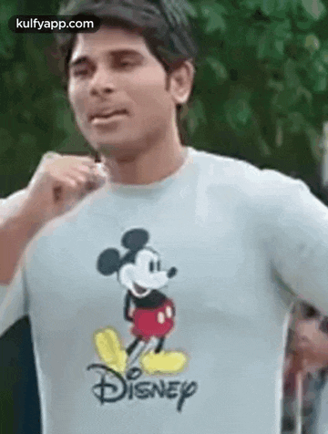 a man is wearing a disney mickey mouse t-shirt and making a funny face .