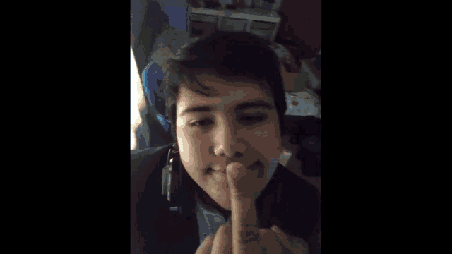 a young man with a tear coming out of his eye is making a funny face with his finger .